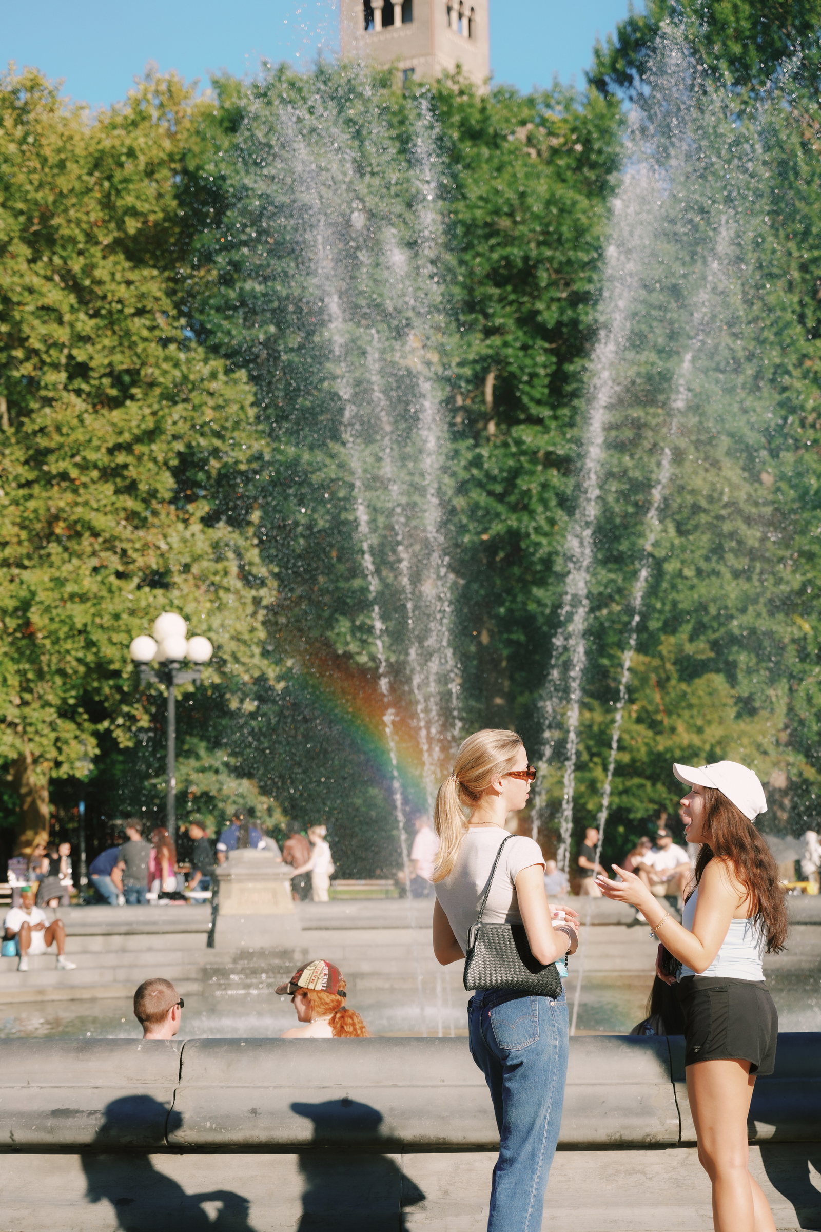 Two people talking beside a park fountain